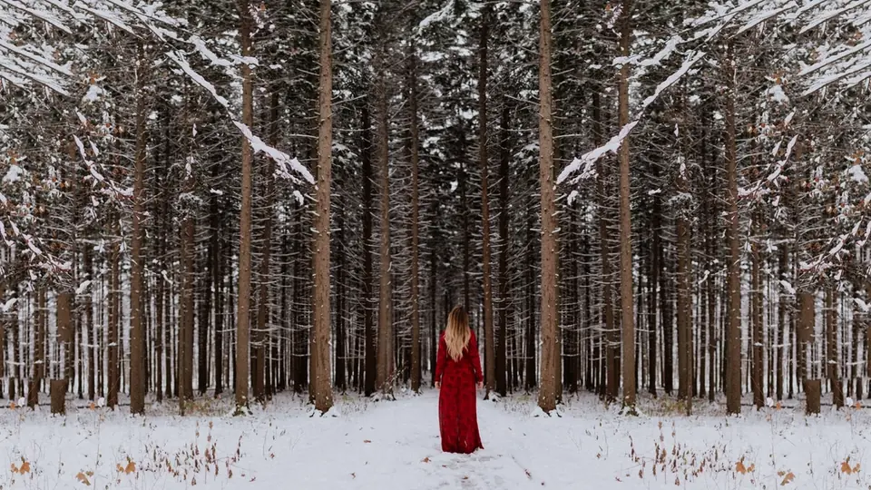 Plan cul Corse : une femme en robe rouge dans une forêt enneigée