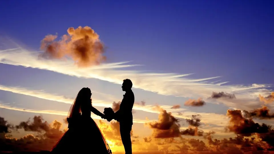 Plan cul Nice : un couple se tient la main en silhouette sous un ciel de couchant