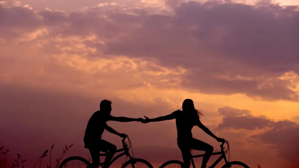 Plan cul Toulon : un couple à vélo se tient la main au crépuscule